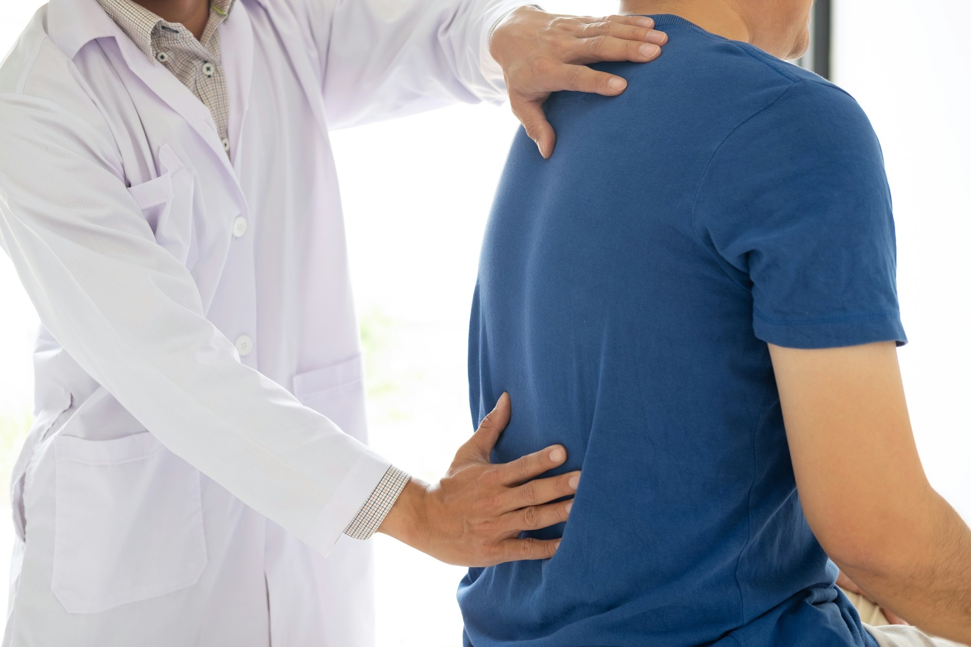 Doctor physiotherapist treating lower back pain patient after while giving exercising treatment on